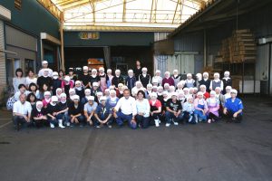 employés de kashiwazaki seika accroupis devant l'usine au japon