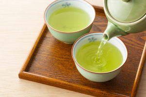 deux tasses de thé vert avec théière dans un plateau en bois