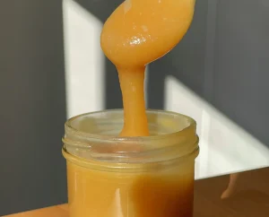 Pot en verre et cuillère qui fait couler du caramel au miso blanc