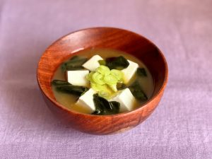Soupe miso japonaise dans un bol en bois, sur une table nappée de nappe couleur lavande