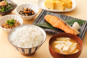 bol de riz, soupe miso, assiette avec morceau de saumon, omelette japonaise sur petite assiette blanche, accompagnement de légumes