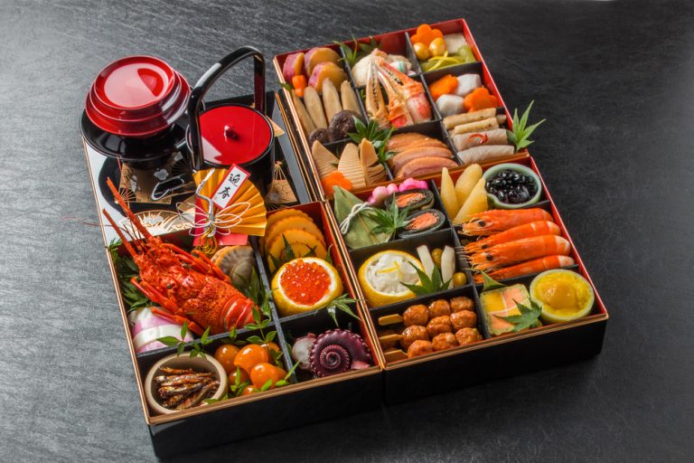 3 boites à bento remplies de petits plats sur fond granite