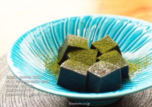 Morceaux de tofu de sésame noirs saupoudrés de matcha dans une assiette creuse bleue