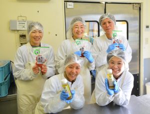 5 femmes en blouses blanches qui tiennent des produits dans leurs mains, dans un laboratoire