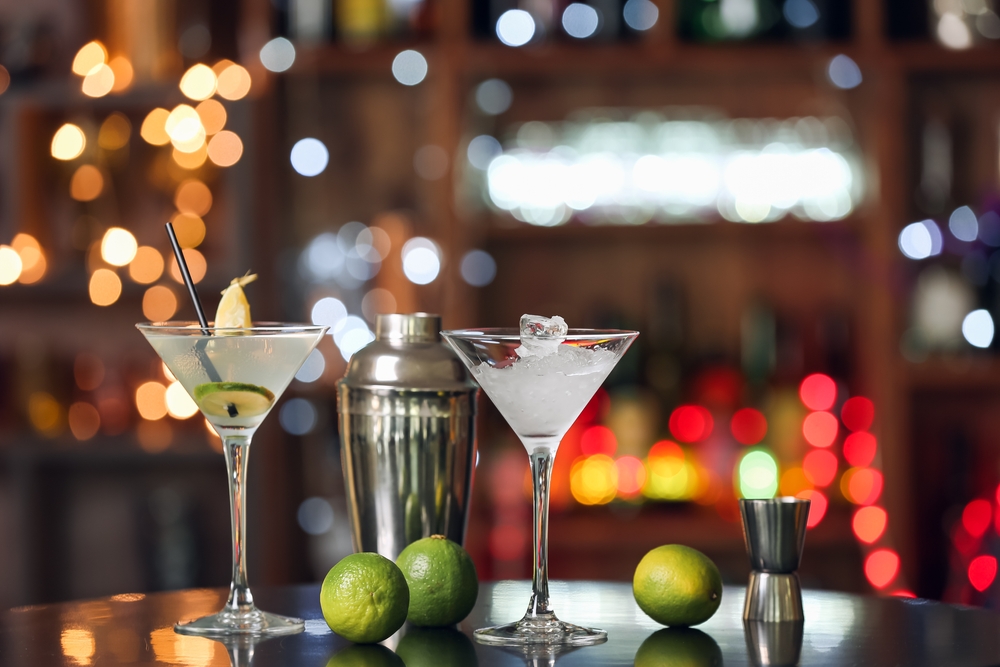 Verres à martini avec shaker et trois citrons verts posés sur une table