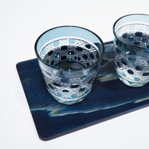 Deux verres avec des motifs bleu indigo posés sur une plateau en bois, sur fond blanc