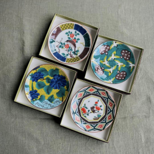 Quatre petites assiettes en porcelaines japonaises colorées sur nappe verte