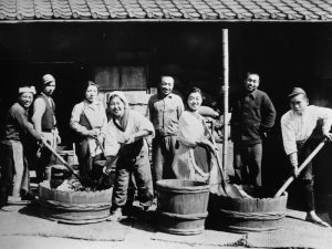 Ancienne photo en noir et blanc de producteurs de miso japonais, 8 femmes et hommes en plein travail