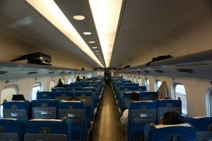Intérieur du Shinansen, avec des sièges bleus de part et d'autre de l'allée, avec des passagers assis