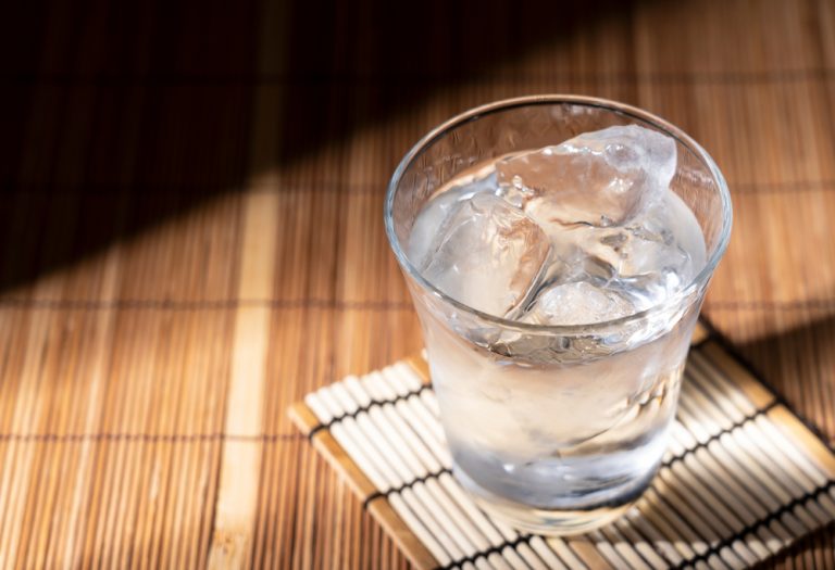 Focus sur un verre d'alcool japonais posé sur une natte en bois